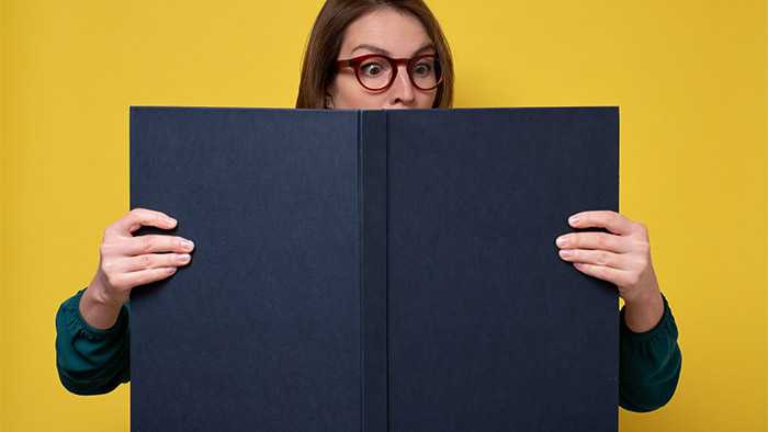 Lady's eyes poking out over top of huge book that she has to hold open with both hands