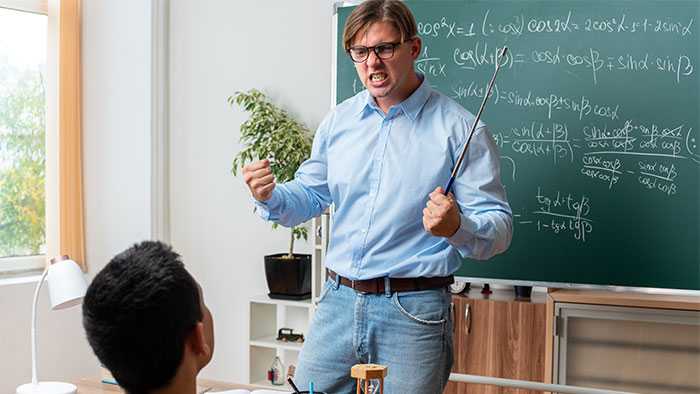 Angry teacher standing in classroom gritting teeth