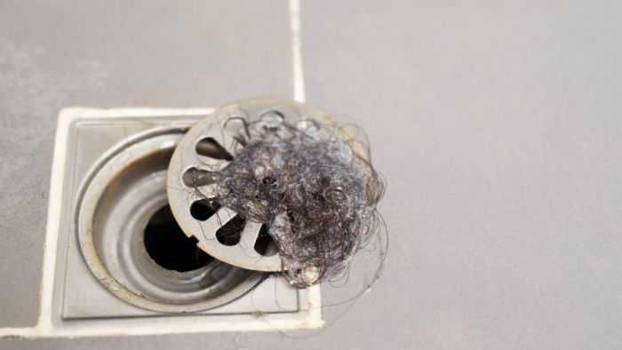 Shower with a glob of hair all wrapped around the drain grate