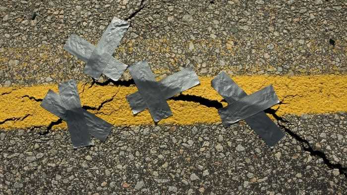 a crack in the road being poorly covered with 3 xs of duct tape