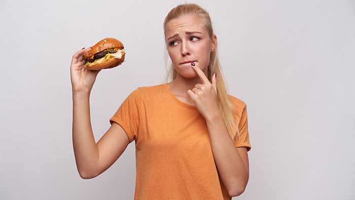 Woman longingly inspects cheeseburger, but struggles to adapt to healthier eating
