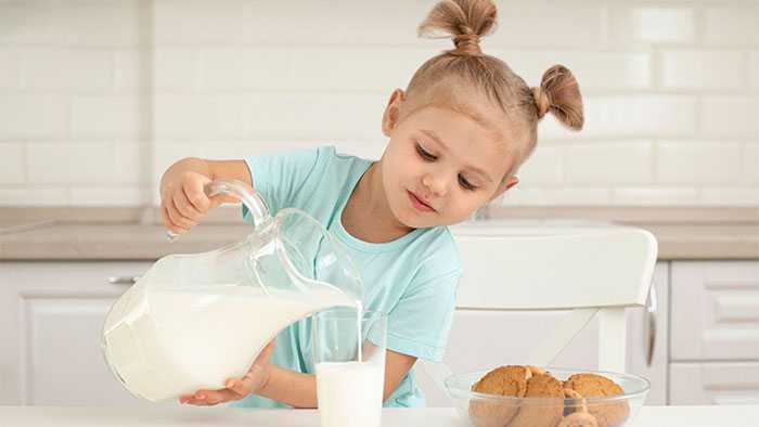 Young girl learning to pour milk on her own