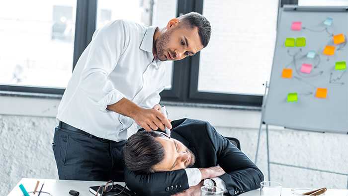 Coworker marking up the face of sleeping coworker