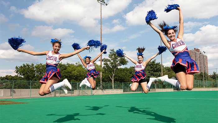 Freeze frame of four cheerleaders captured mid jump 