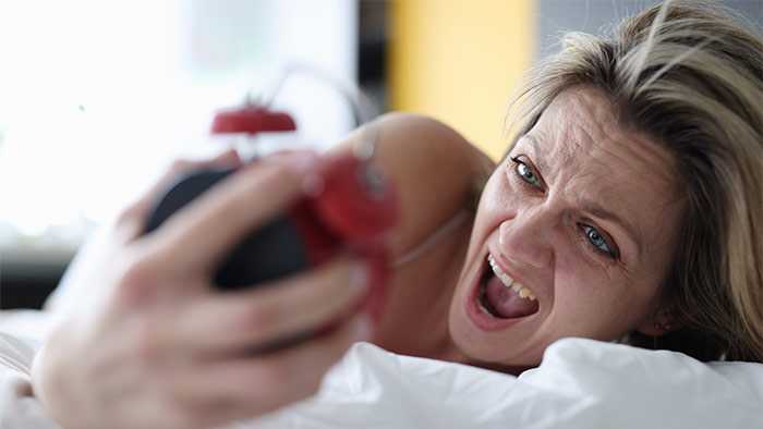 Lady waking up with alarm clock in hand yelling
