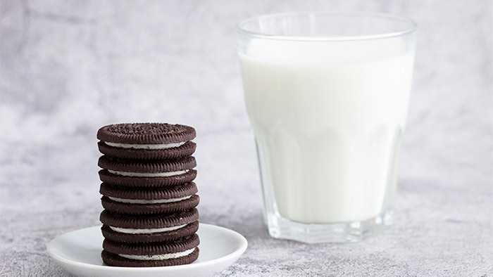 Your favorite chocolate sandwich cookies stacked next to a glass of milk