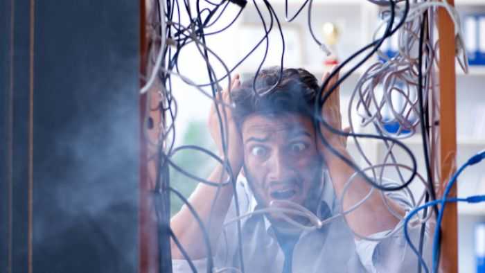 IT guy indecisively watching a mass of wires smoke