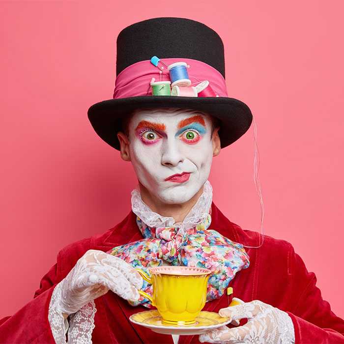 Perplexed mad hatter drinks tea with one eyebrow raised in judgment