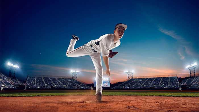 Pitcher frozen post pitch in a baseball field at night