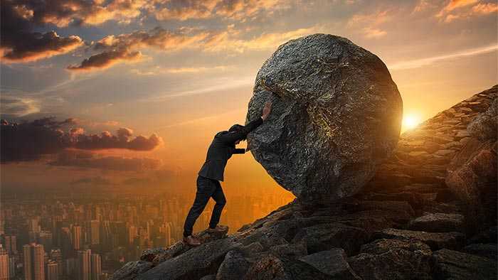 Scrum Master pushing a rock up a hill signifying perpetual up-hill battle