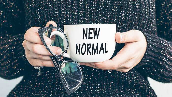 Midsection shot of girl in sweater holding a mug with phrase new normal