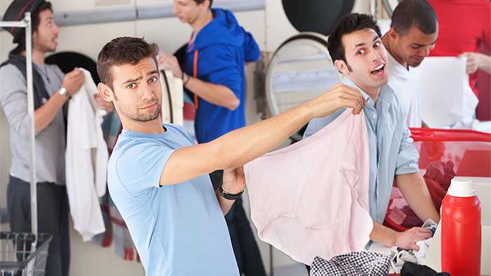 Questioning dude at laundromat holds up giant pair of panties while bystander looks on in disbelief