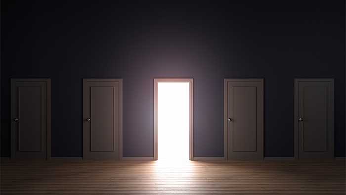 On a wall of five doors, the middle door stands open with bright light implying an opportunity