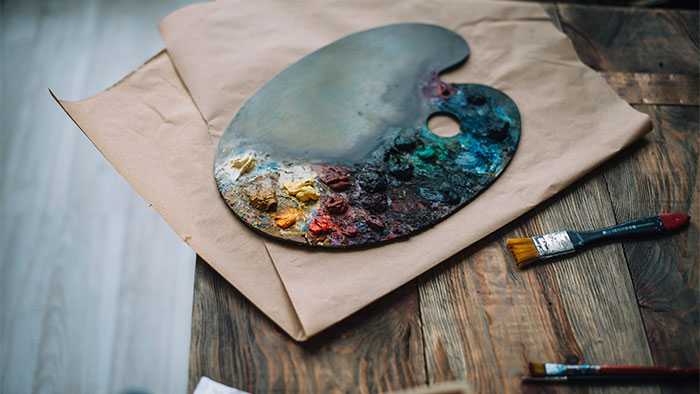 Color palet with mixed paint and brushes laying on table