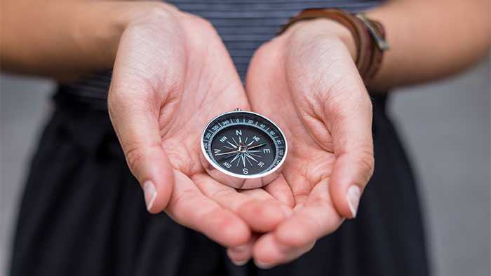 Caring hands cradling a compass