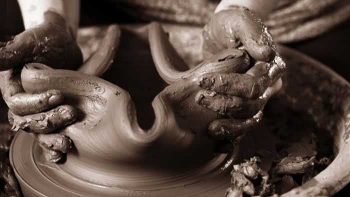 Hands squishing clay pot into unusable shape