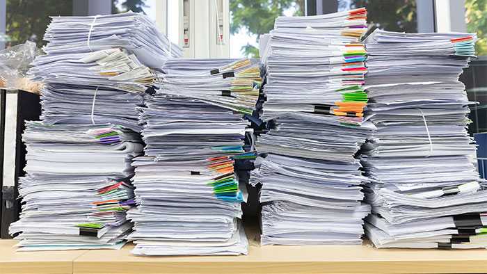 Giant stacks of paper on a desk with information no one will ever read