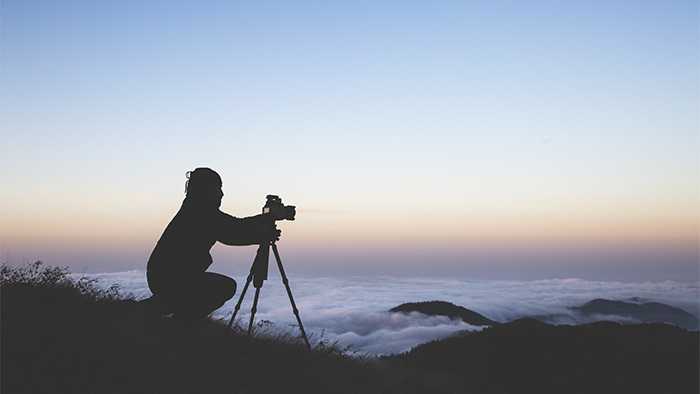 A silhouette of a photographer setting up the camera to shoot the sea of clouds during sunset