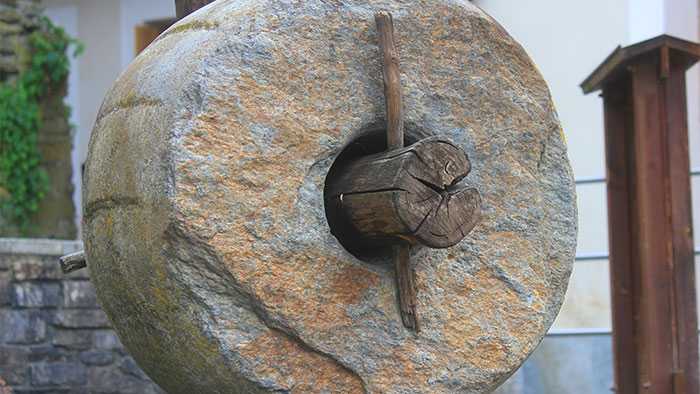 Really large stone wheel with tree trunk through middle as axle